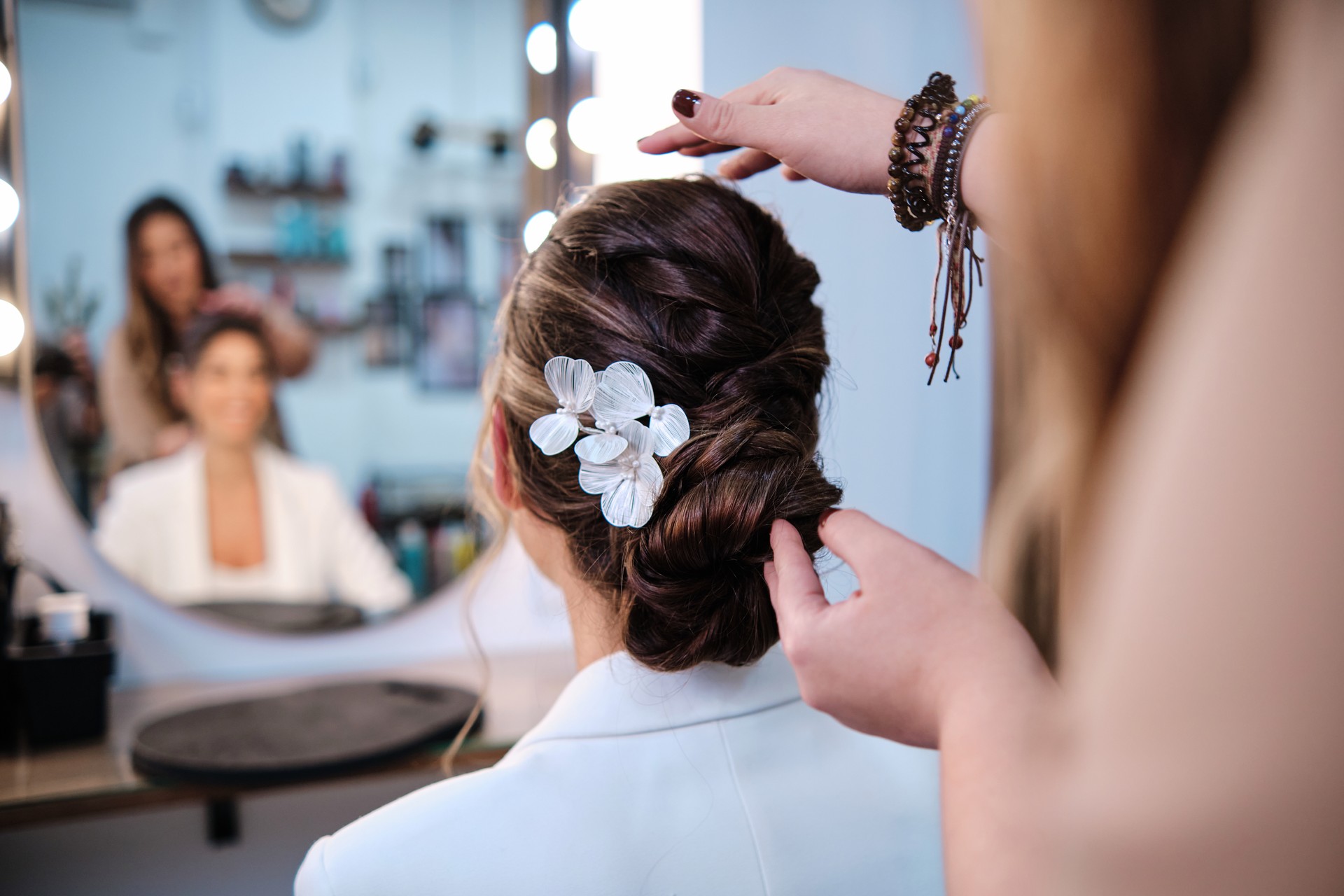 Professional hair stylist finishing a hairstyle for a bride at the hair salon.